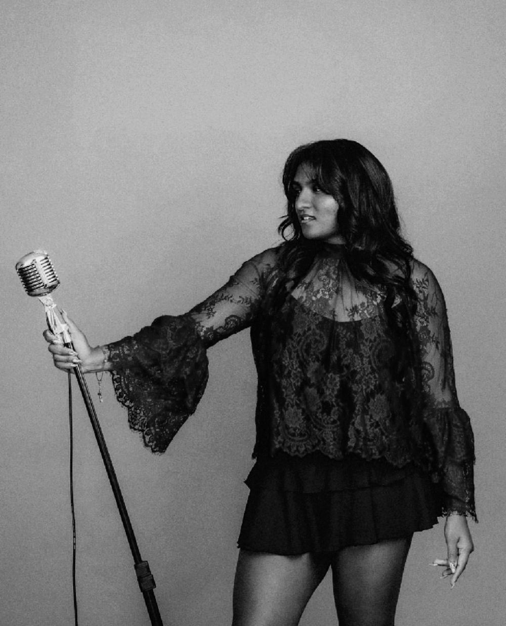 Mashi J singing into a vintage microphone, black and white
